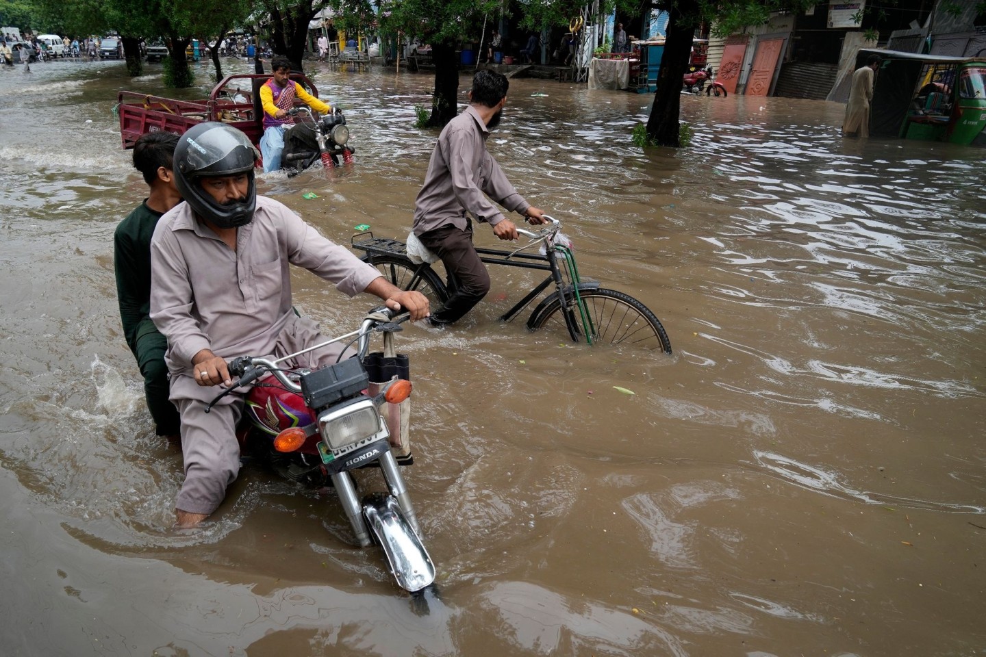 Motorradfahrer auf einer überschwemmten Straße im pakistanischen Lahore.