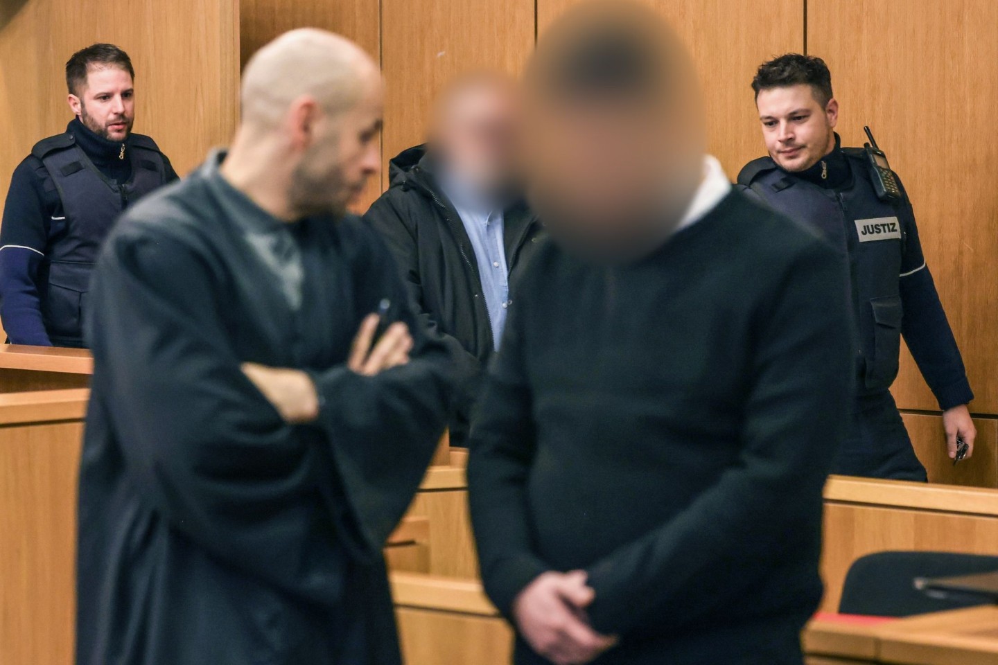 Die Angeklagten werden von Justizbeamten in den Gerichtssaal geführt.