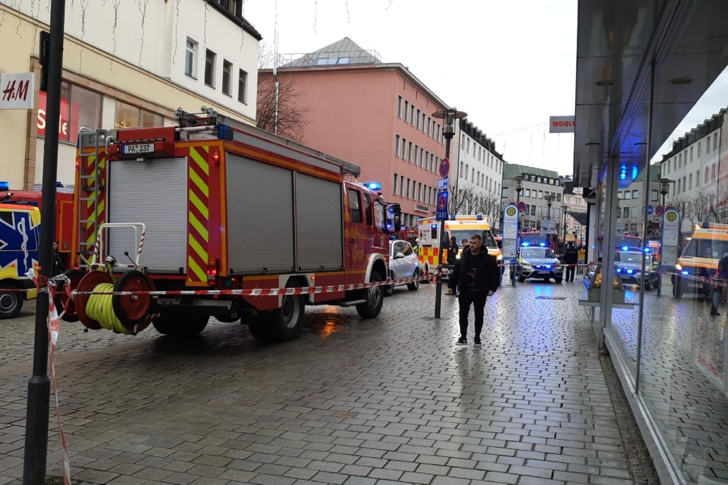 Einsatzkräfte von Feuerwehr und Rettungsdienst stehen am Freitag in der Innenstadt am Einsatzort.