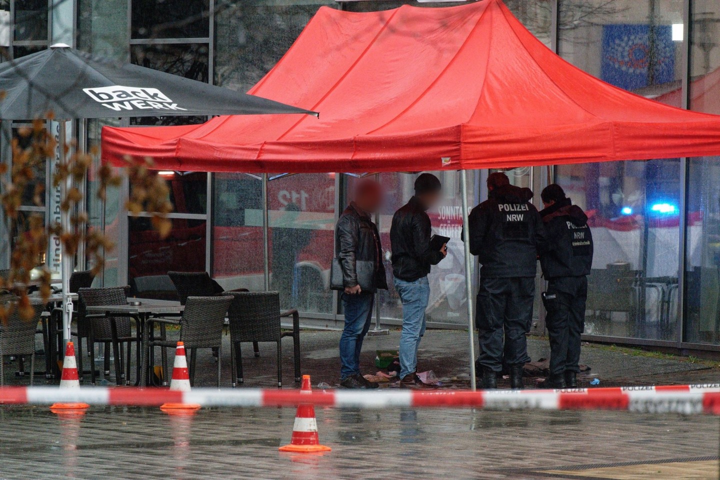 Polizeibeamte untersuchen unter einem Zeltdach den Tatort in Gummersbach.