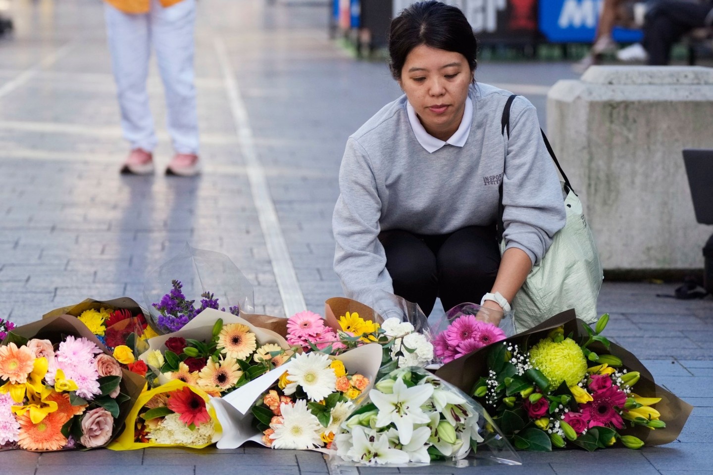 Eine Frau bringt Blumen zu einer improvisierten Gedenkstätte an der Bondi Junction.