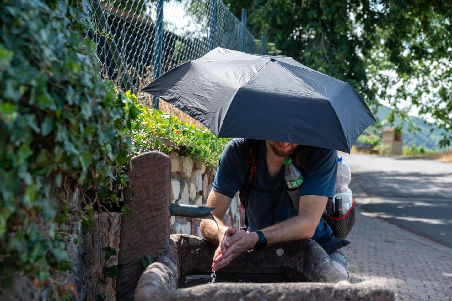 Erfrischung und Sonnenschutz: Ein Wanderer auf einem Wirtschaftsweg in Rheinland-Pfalz.