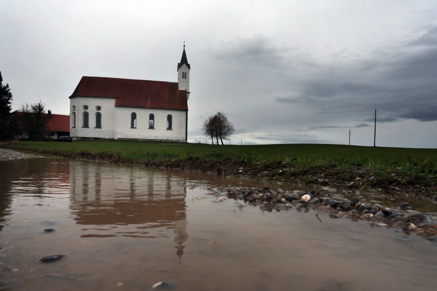 Regenwolken über der Wallfahrtskirche Sankt Alban im bayerischen Aitrang.