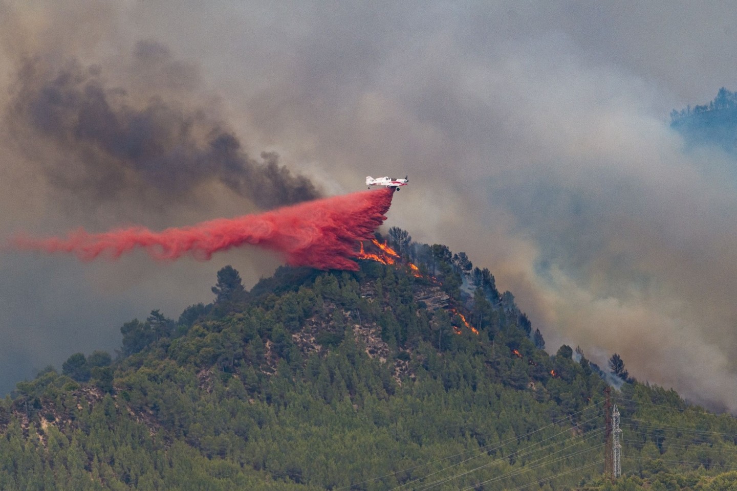 Ein Flugzeug wirft Löschmittel auf die Flammen eines Waldbrandes im spanischen Castellgali.
